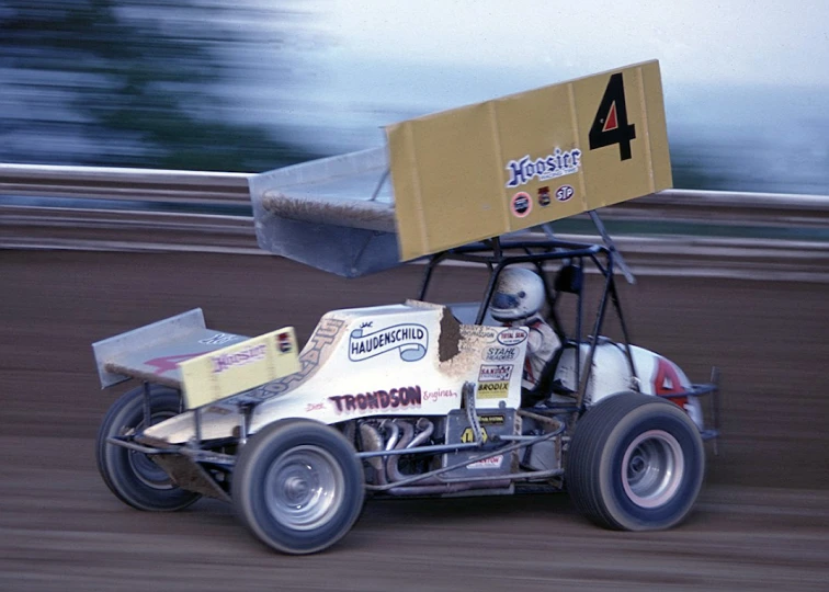 a modified racing car driving down the dirt track