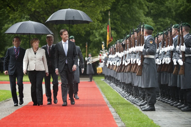 three men and two women in uniform walking down a red carpet