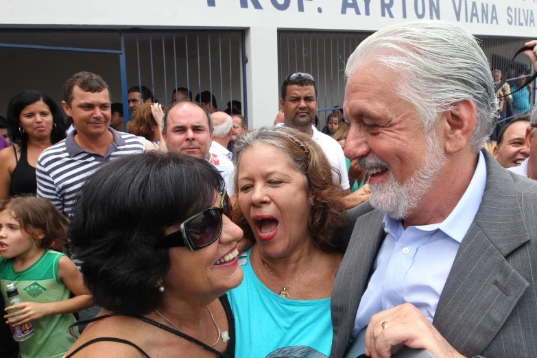 a man and two women laughing while people look on