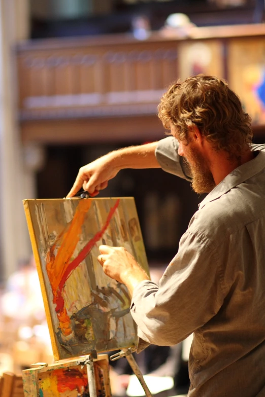 man painting in a small room on easel