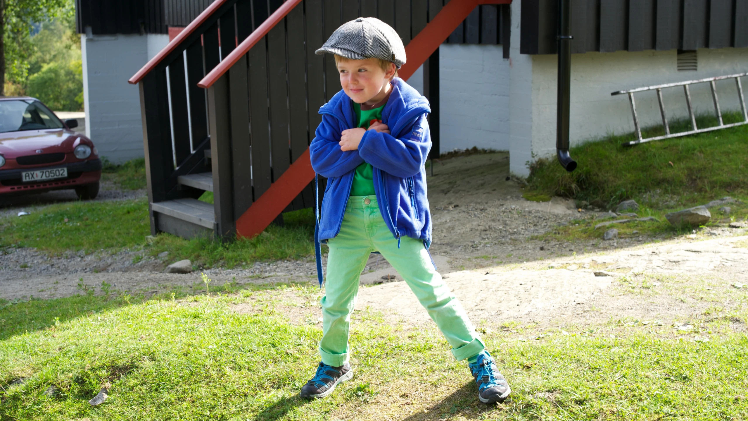a  poses for the camera wearing green pants and a blue jacket