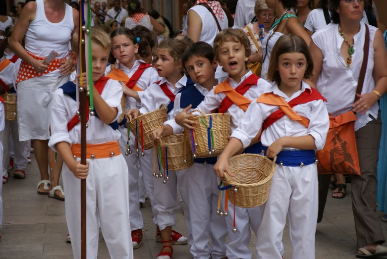 several children in white and orange outfits standing outside