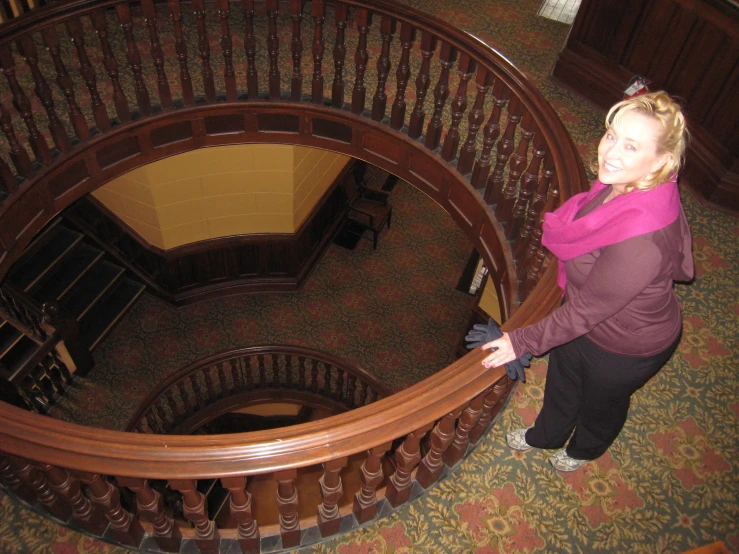 a woman standing on a spiral staircase with a pink scarf