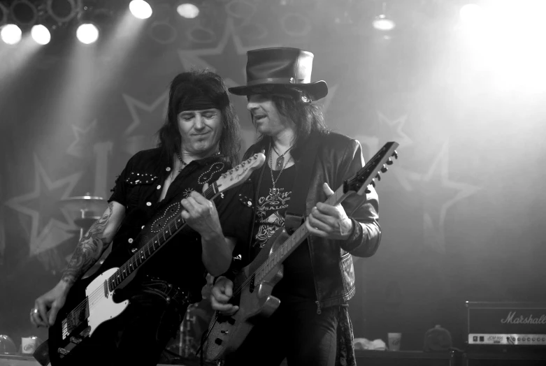 two men wearing top hats playing guitars at a concert