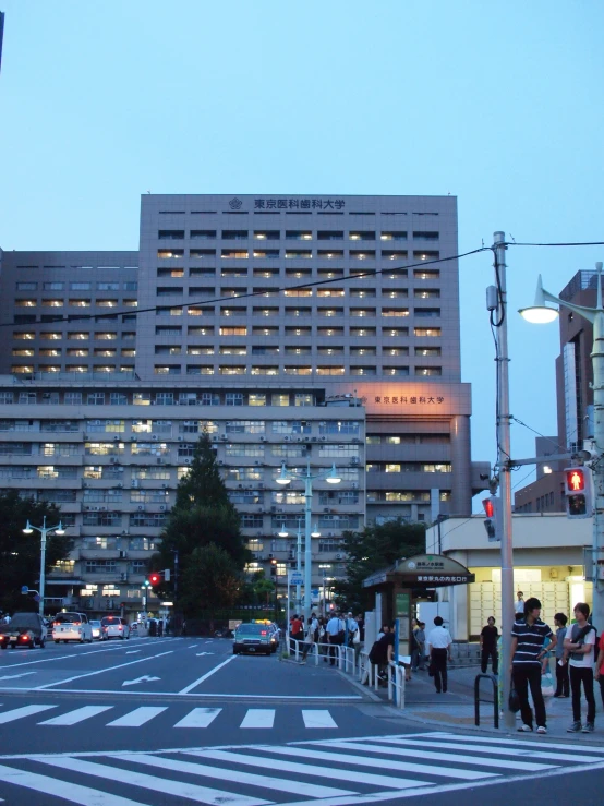 a busy city intersection at twilight with a large building