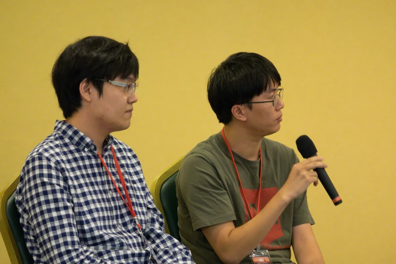 two guys sitting next to each other while holding microphones