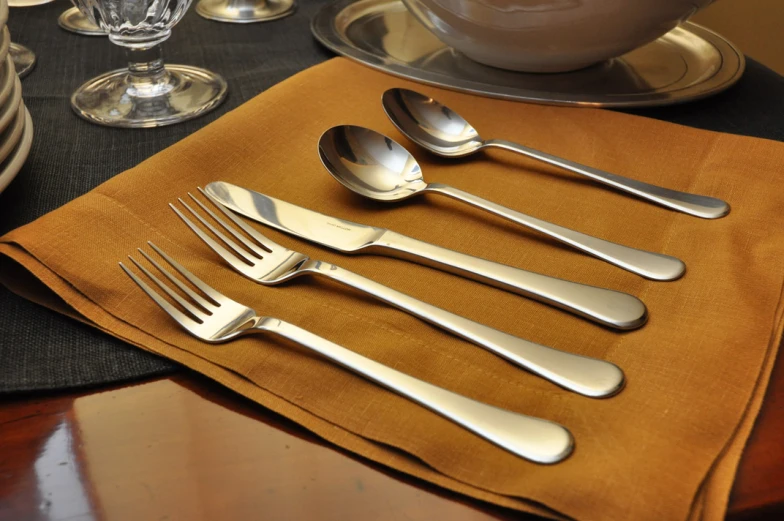 six silver spoons are set next to an empty cup