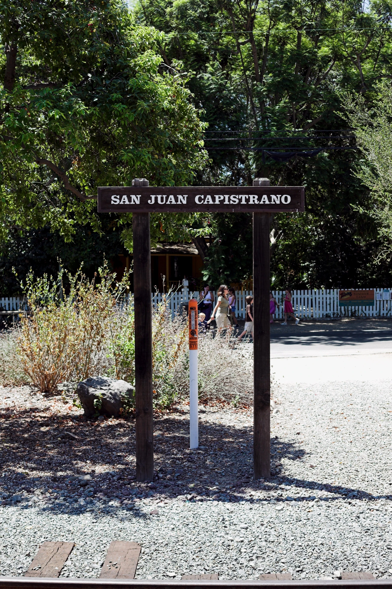 a black and white sign sitting on top of a dirt road