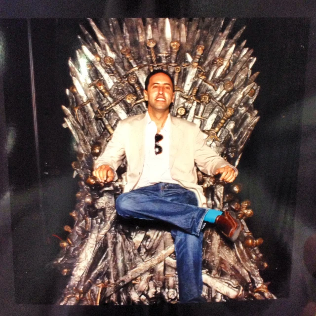 a man sitting on a game of throne made of liquor bottles