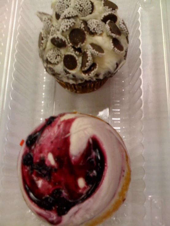 two cupcakes and a muffin on plastic tray