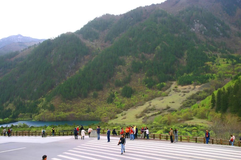 a crowd of people walking across a wooden walkway next to mountains