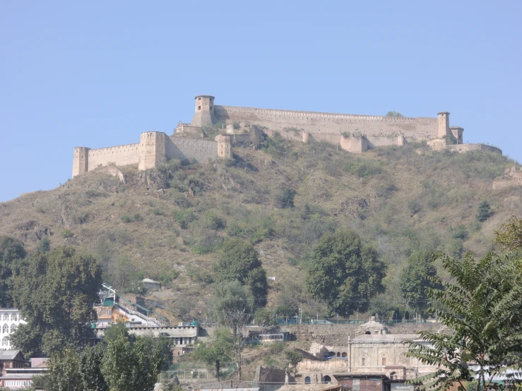 a large building sits on a hill near trees