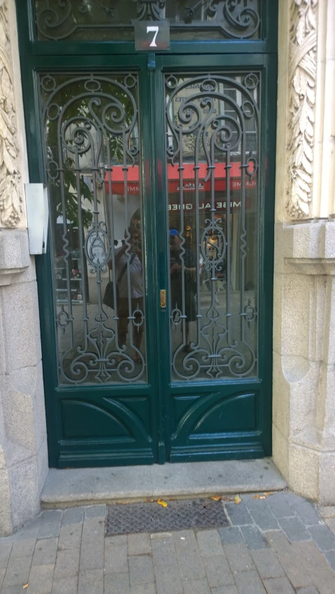 a green double door with decorative iron work