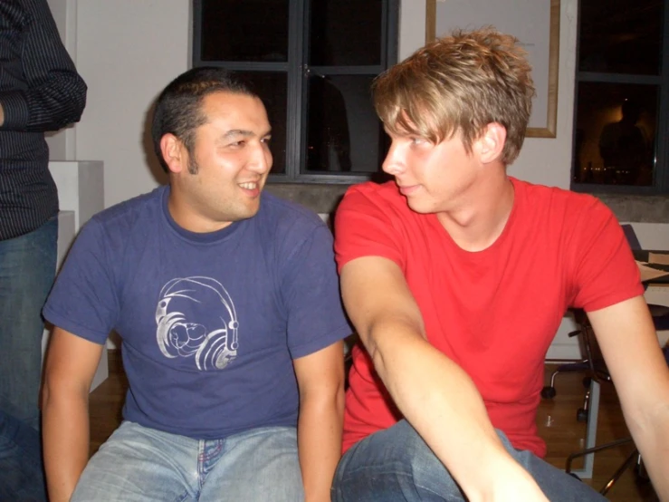 two young men sitting next to each other in front of chairs