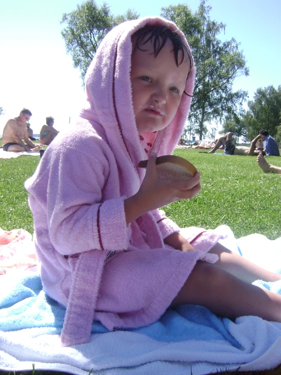 the little girl is sitting on the blanket holding her hair brush