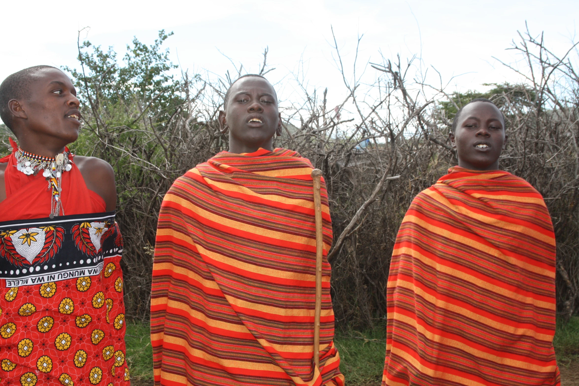 three black people in bright clothing standing next to each other