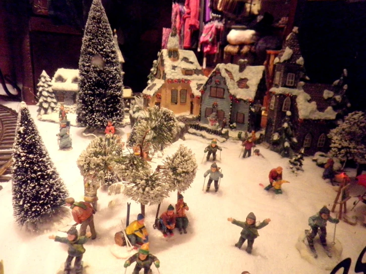 a miniature christmas village with people and snow scenes
