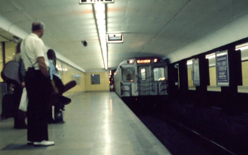 people stand waiting to board the subway