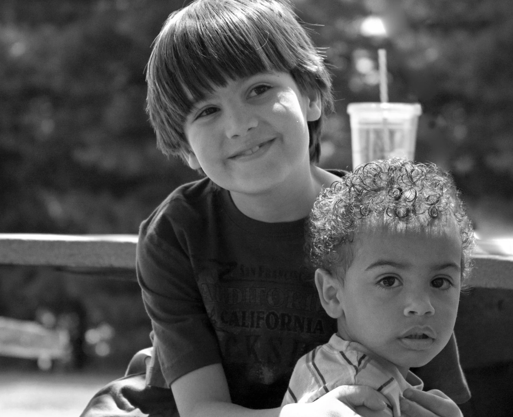 two young children sitting next to each other on a bench