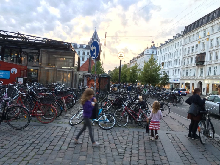 a group of people walk by a lot of parked bikes