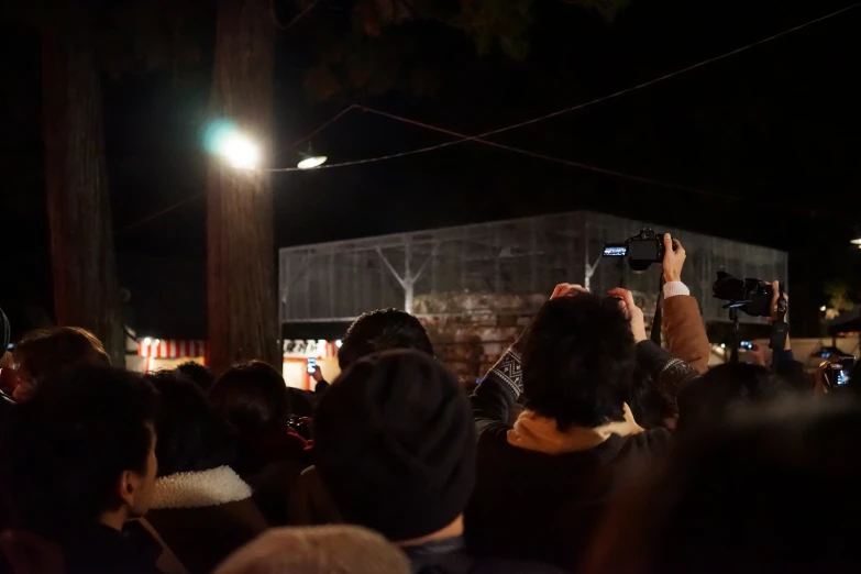 a crowd is standing around at night taking pictures