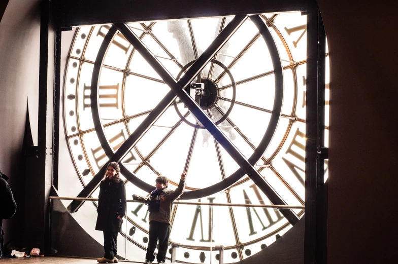 people stand next to the huge clock in the building