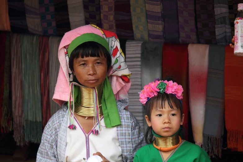 two woman wearing various headsgear and neck jewelry