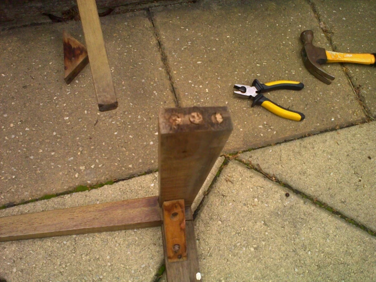 a hammer, pliers, and other tools laying on concrete