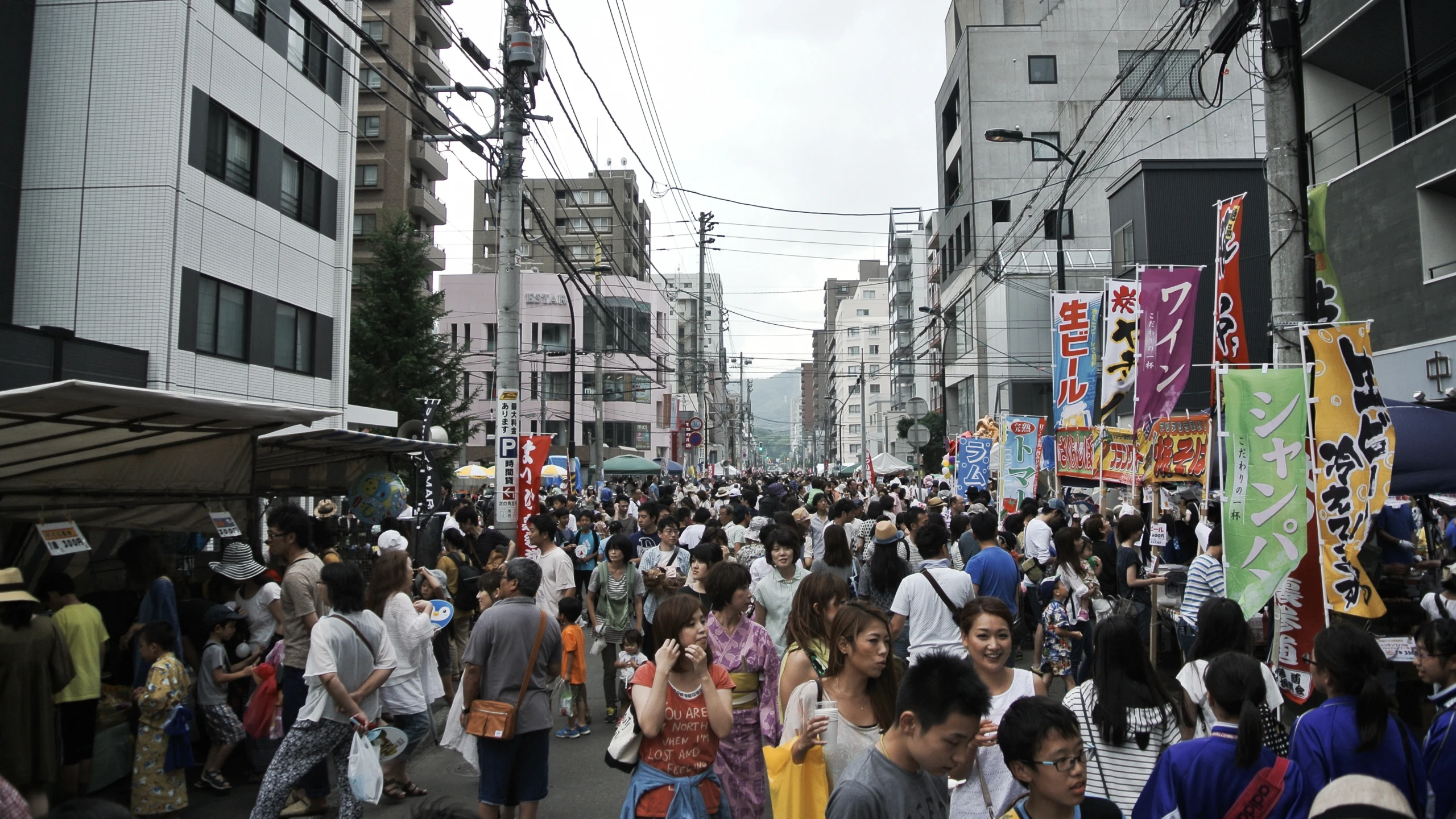 a crowded city street with a lot of people walking down it