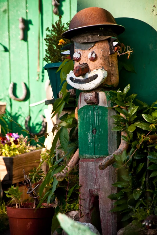 wooden scarecrow on side of building near green door