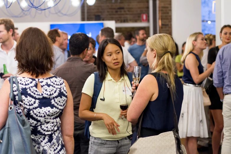 a large group of people standing around talking and drinking