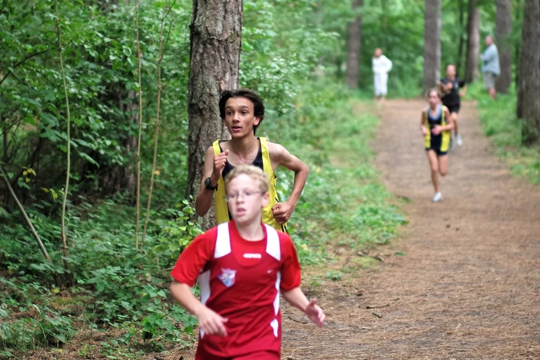 several people are running in the forest by some trees