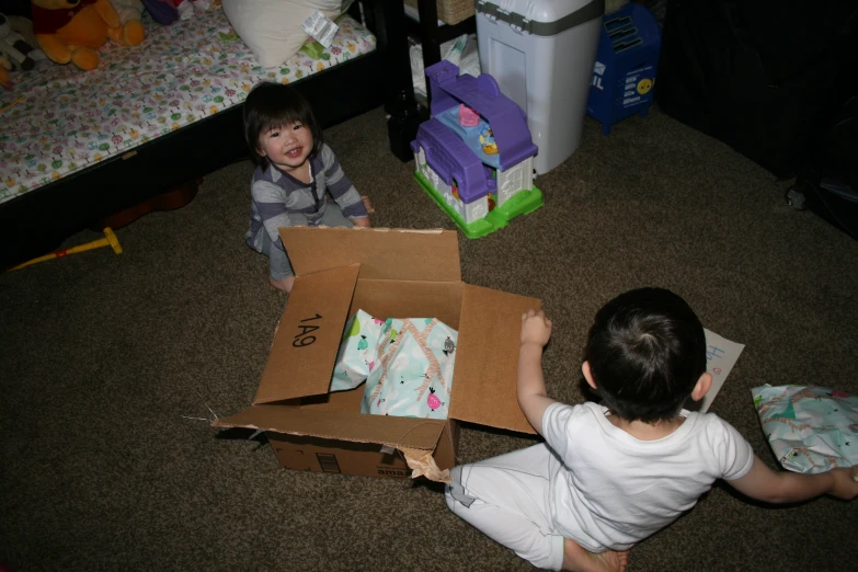 two young children playing with a very large toy box