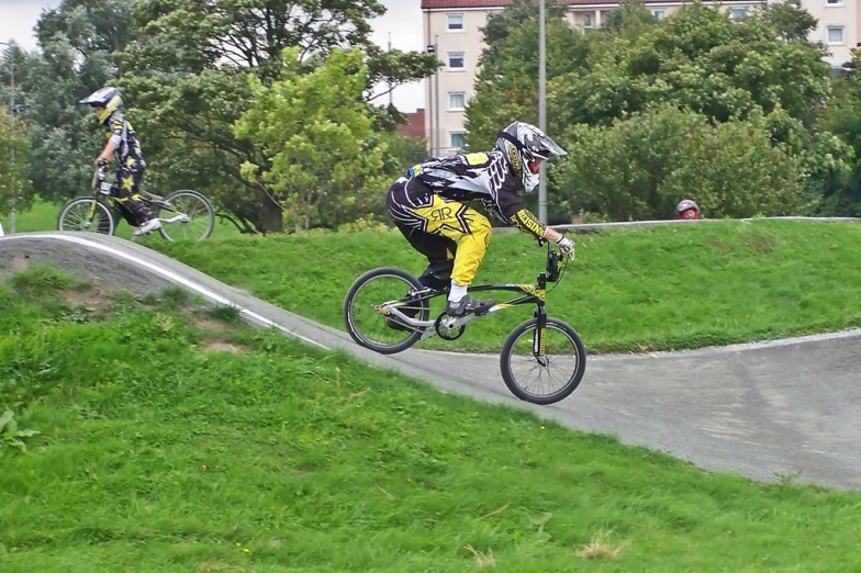 a man in yellow and black bike suit jumping over a ramp