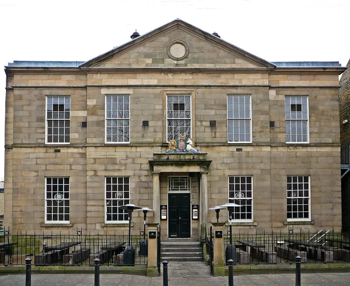 this is a large tan colored stone building with black iron fences