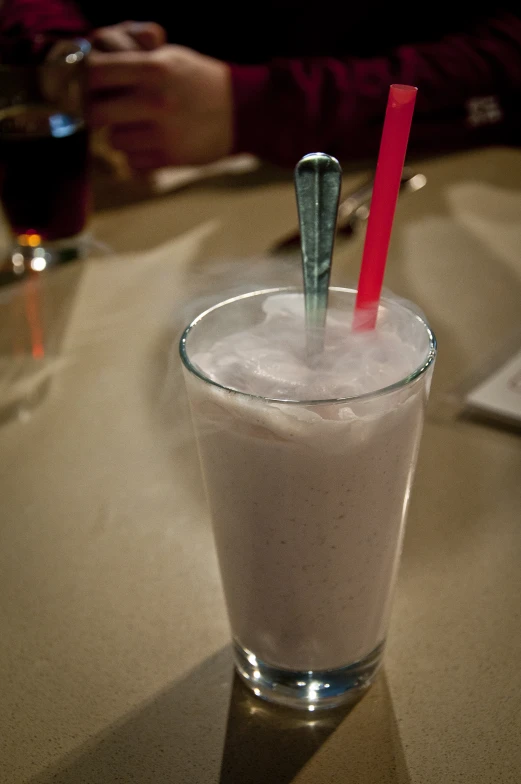 a beverage with a red straw inside is sitting on a table