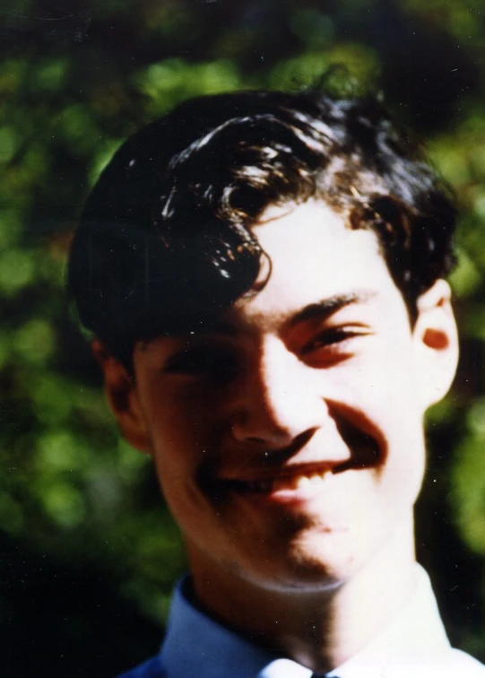 a man with curly hair, wearing a blue shirt and a tie