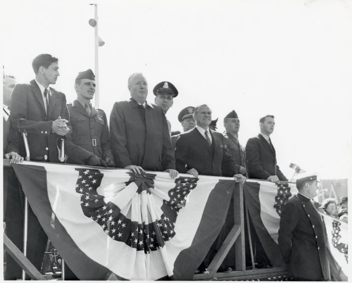 a group of men standing in front of a large american flag