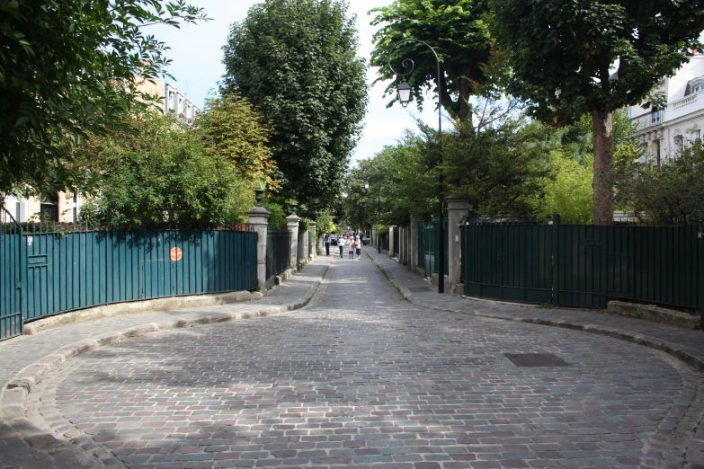 a narrow cobblestone street with a blue gate