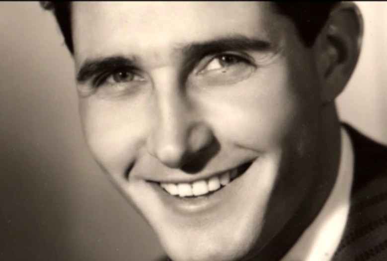 a black and white po of a smiling man in a tuxedo