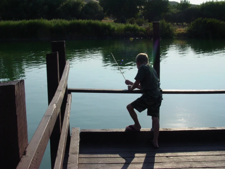 a person standing at the end of a wooden pier next to water