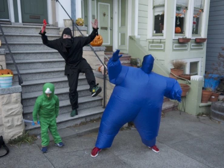 a boy and girl in their costumes outside of a house