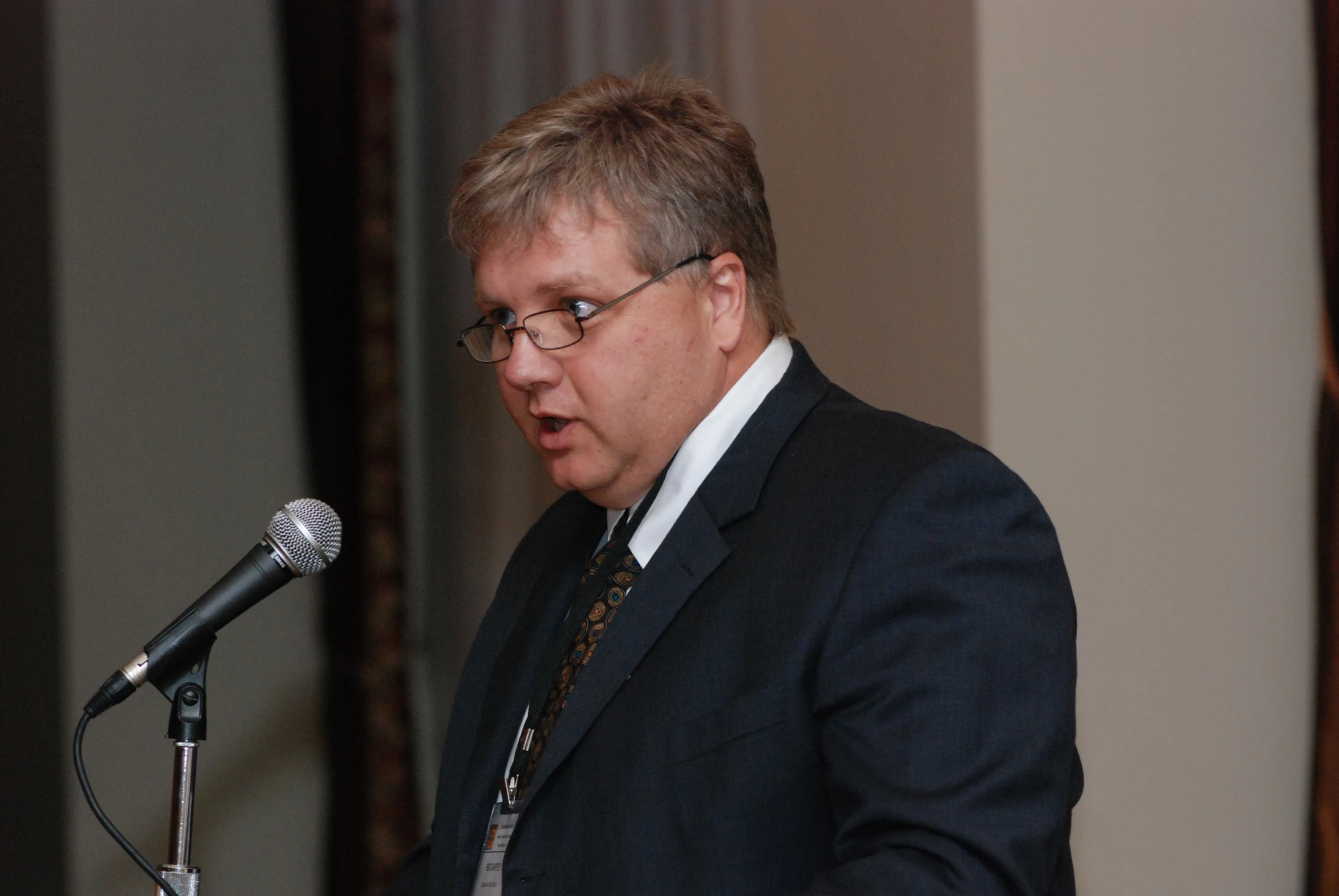 a man in suit and tie giving a speech