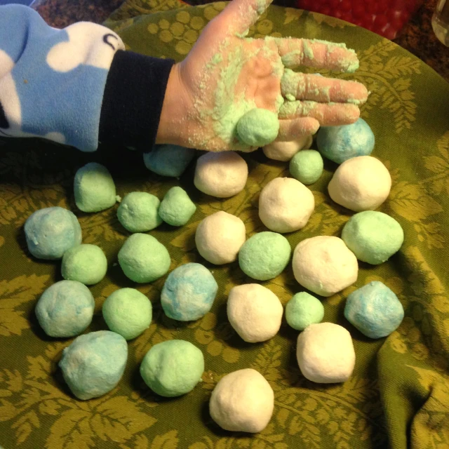 a person's hand on a green surface with powdered sugar