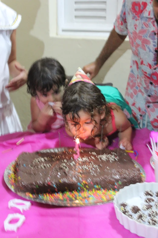 two children sitting in front of a chocolate cake