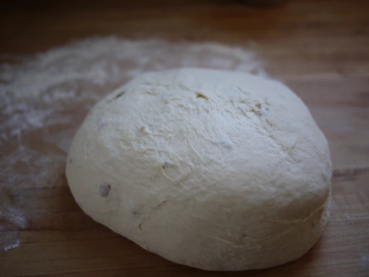 uncooked bread ball sitting on top of a wooden surface