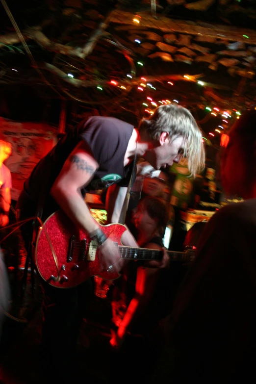 a guy holding a red guitar near some people