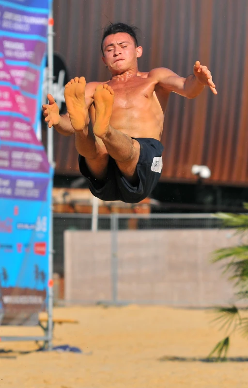 a man jumps in the air shirtless, while on a surfboard