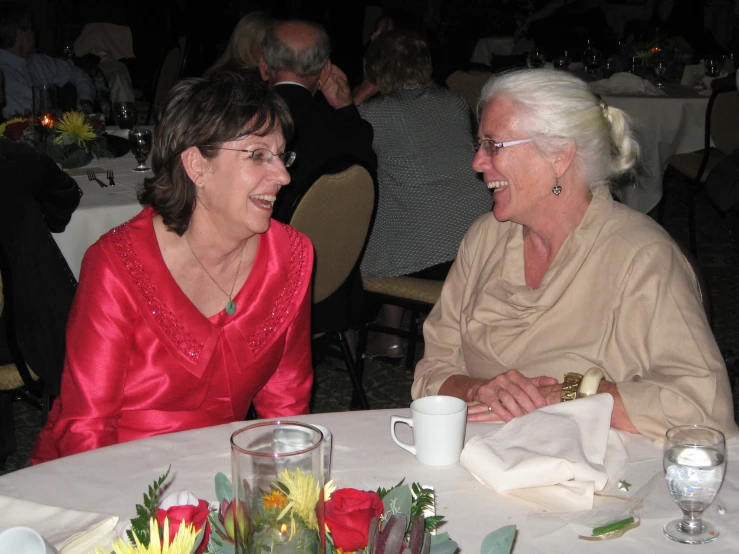 two woman talking to each other at a table
