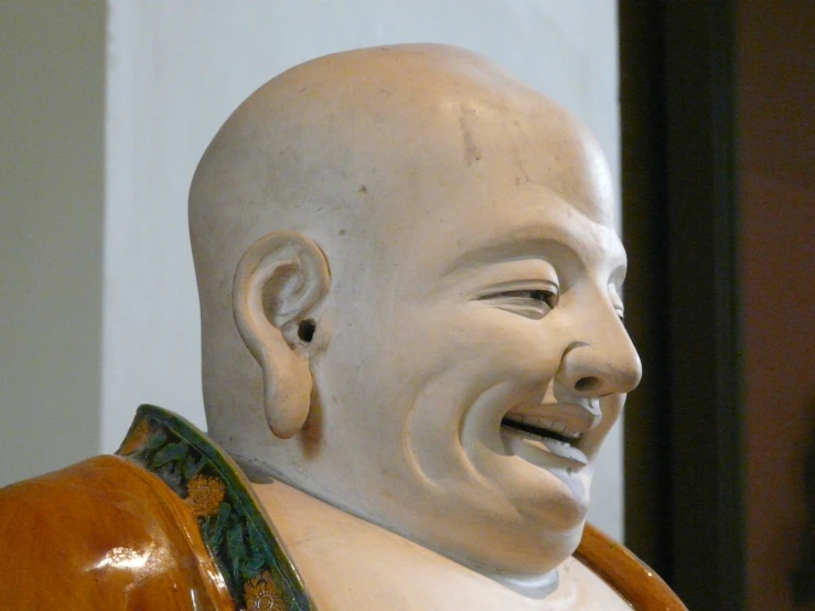 statue of a laughing man in orange with large gold earring